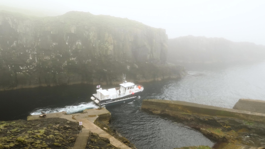 Boat leaving a harbor in Mykines Island hidden in heavy fog, Faroe Islands. High quality 4k footage.