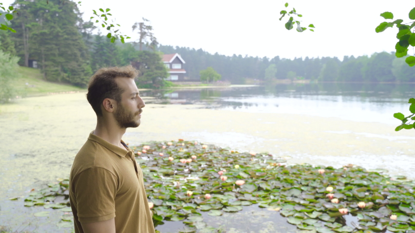 Breathing in the forest, breathing fresh air.
Young man breathes and happy in nature by the lake.
