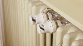 hand turns the radiator knob to lower the temperature of the house heating,  winter energy crisis management video concept