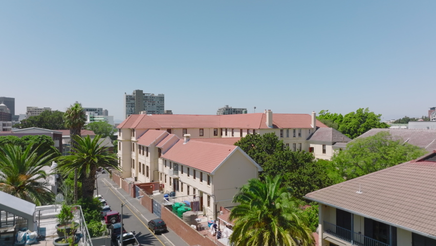 Aerial ascending footage of town development in large city on sunny day. Houses with red roof and multistorey buildings. Cape Town, South Africa