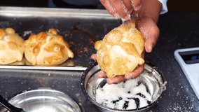 Horizontal video of the hands of an unrecognizable person putting sugar cubes in a pan de muerto.