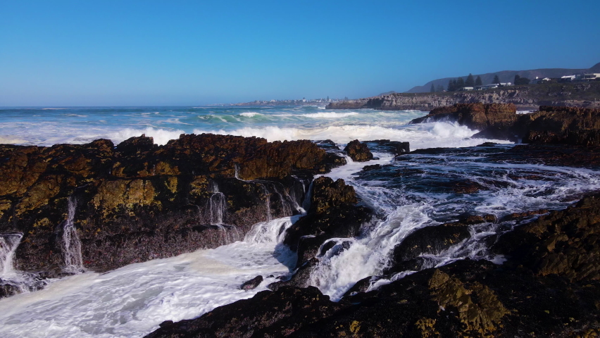 Slow motion aerial of wave crashing over rugged rocks on coastline, Royalty-Free Stock Footage #1095052255