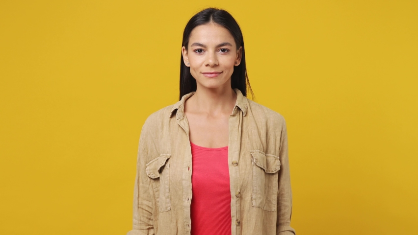 Young joyful jubilant surprised shocked latin woman she wear beige shirt pink t-shirt say wow omg what spreading hands doing winner gesture put arms on face screech isolated on plain yellow background
