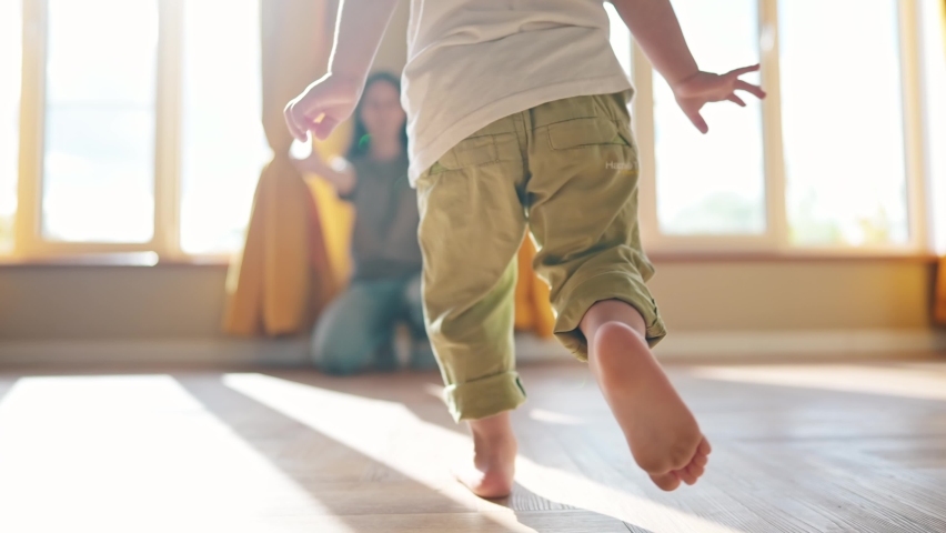 baby runs to mom at home. a child with bare legs runs across the floor to his mother against a sunny window. happy family kid dream concept. kid running back view at home lifestyle hugging mom Royalty-Free Stock Footage #1095054577