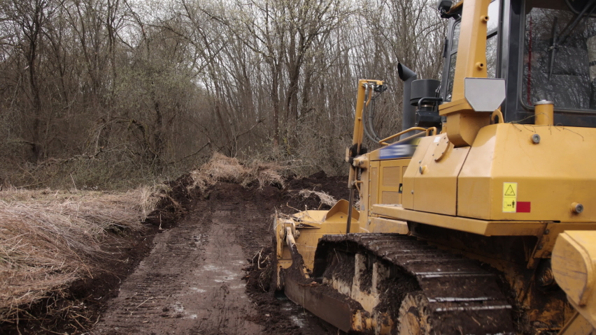 Construction machinery equipment, earth building bulldozer, earthmoving machine technology, industrial erection concept. Bulldozer working on mud at a construction site