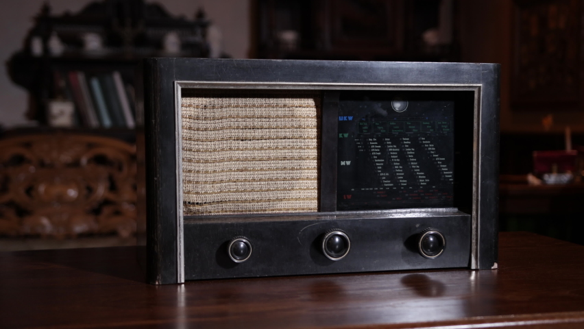 Stylish retro radio player, retro broadcast radio receiver circa 1950 against a vintage interior background. Listen to music concept in old style, the FM channel is playing.