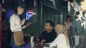 Video of young waitress using application on digital tablet computer to order what the couple want for lunch in a restaurant - Powered by Shutterstock - Get 15% off with code: PIKWIZARD15