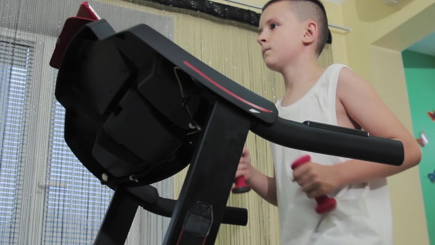 Boy running on a treadmill with dumbbells in his hands