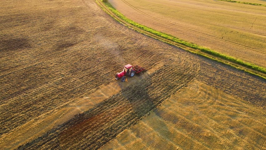 Tractor plowing field in cultivated land and soil tillage aerial view. Concept of work in agronomic farm for making business and having profit from production organic food Royalty-Free Stock Footage #1095069447