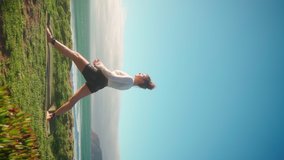 Yoga exercises with ocean view on background. Caucasian woman doing yoga training on seashore. Healthy lifestyle concept. Mid adult female practicing yoga and flexibility. Vertical video Warrior pose