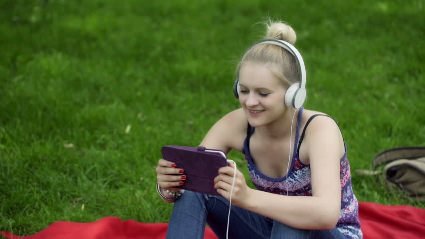 Girl listening music on tablet and smiling to the camera
