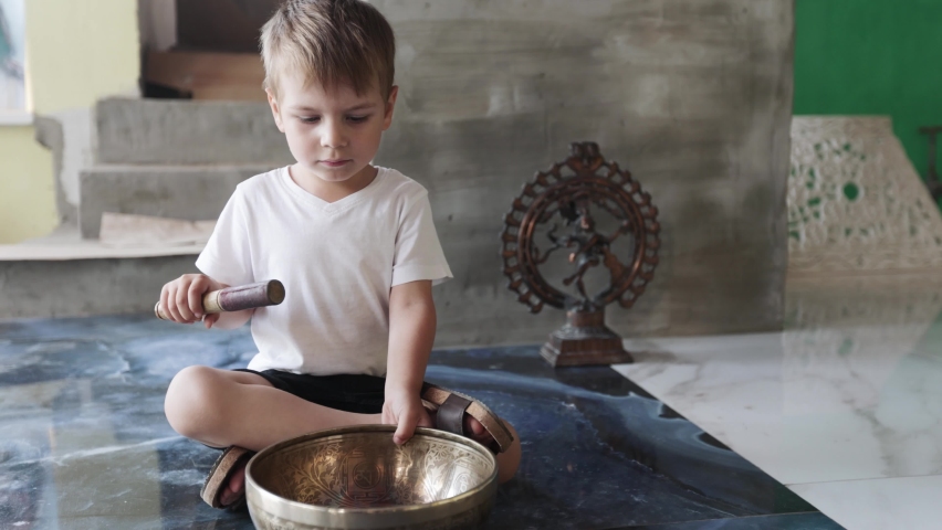 Boy playing singing bowls sitting on the floor