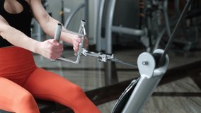 A woman in the gym performs exercises on a rowing machine. Seat pulls weight. High quality 4k video
