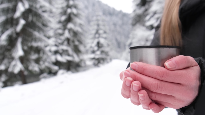 Close-up of girl drinking tea over winter nature background outdoor. Beautiful winter forest