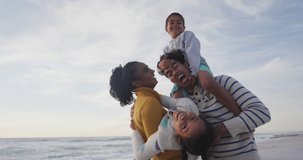 Animation of merry christmas text over happy biracial parents and children laughing on beach. Christmas, holidays, family, festivity, tradition and celebration concept digitally generated video.