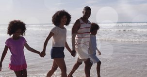 Animation of christmas decorations over happy biracial parents and children walking on sunny beach. Christmas, holidays, festivity, family and celebration concept digitally generated video.