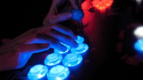 Man hands playing retro arcade machine game and pushing bright blue buttons in dark room - close up view. Gaming, 80s, hobby, vintage, technology, retro video game and leisure time concept