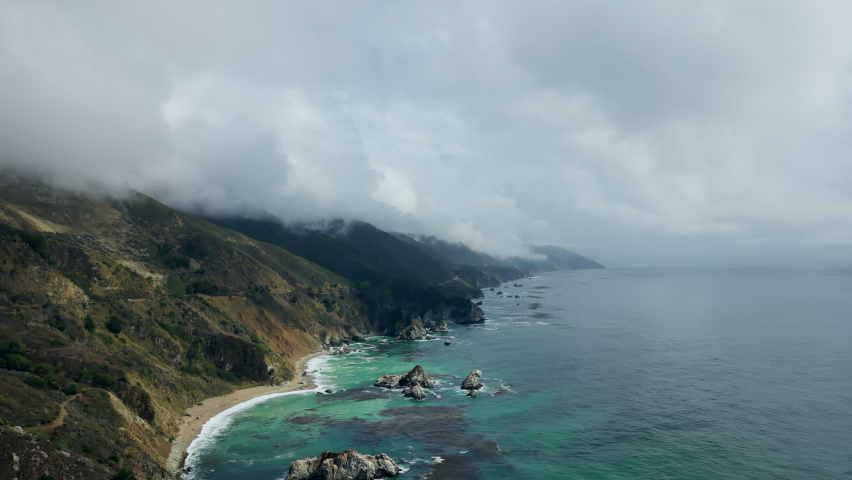 Natural Aerial drone flying over Big Sur California coast beach cloudy fog the ocean clouds sky sun sunny waves crashing. Travel view scene peak weather wave. High quality 4k footage.