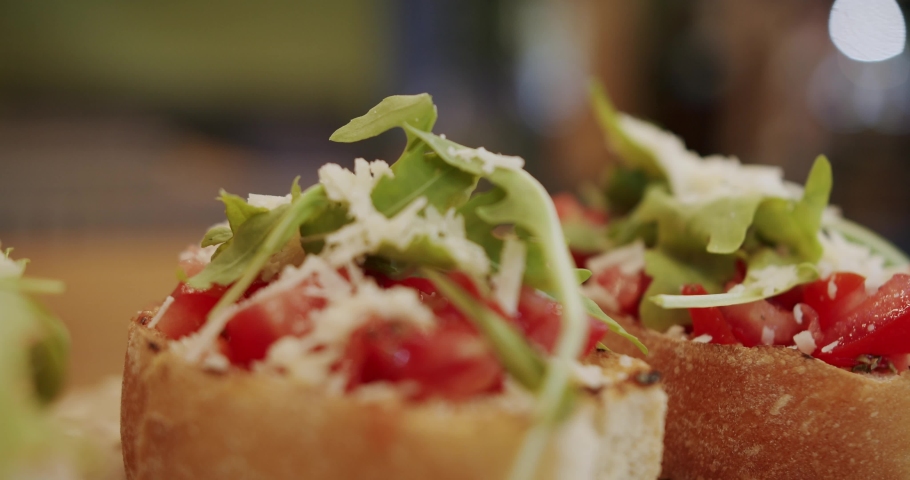 Delicious bruschetta sourdough toast with cherry tomatoes, cheese and arugula. traditional italian breakfast brunch dish at a restaurant, 4K shot . Italian Bruschetta crostini. Healthy, vegan food.