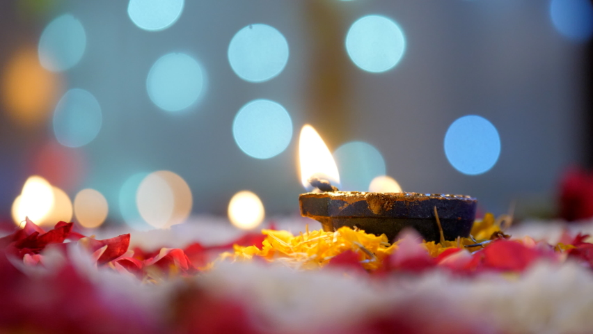 Closeup shot of a Diwali Diya - Diwali lamp kept on the floor with flower rangoli, Diwali festival, Diwali decoration . A brightly burning colorful Diya kept on a floral platform on the occasion of... | Shutterstock HD Video #1095090505