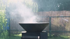 Round black modern grill . Round table-cooking surface. Steam comes out of the grill. Slow motion video