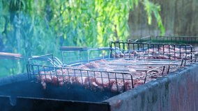 Fresh meat for barbecue, fried on fire. Selective focus. Grilled pork meat. Cooking barbecue on the grill with smoke. Picnic in nature. Slow motion horizontal video