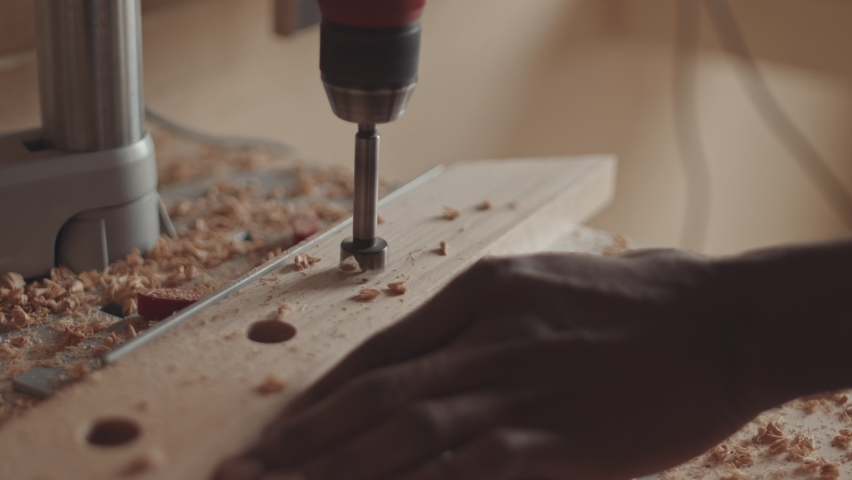 Close up of unrecognizable African American carpenter drilling plank using automatic drill with circular crown drill bit