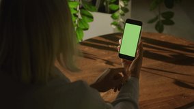 Woman swipe on a smart phone with green screen chroma key sideways