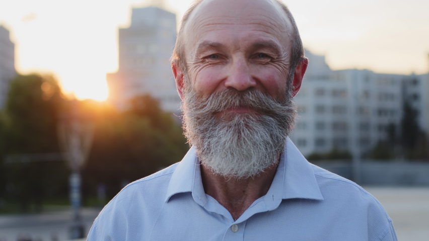 Retirement life is great. Happy smiling contented grandfather looking at camera posing outdoors. Attractive, intelligent, elegant elderly mature old man enjoying good weather on weekend Close-up Royalty-Free Stock Footage #1095108475
