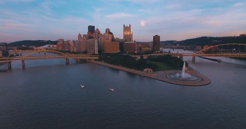 An aerial approach just off the top of the water towards Pittsburgh, Pennsylvania and Point State Park at sunset. (Pittsburgh PA, July 2015)
