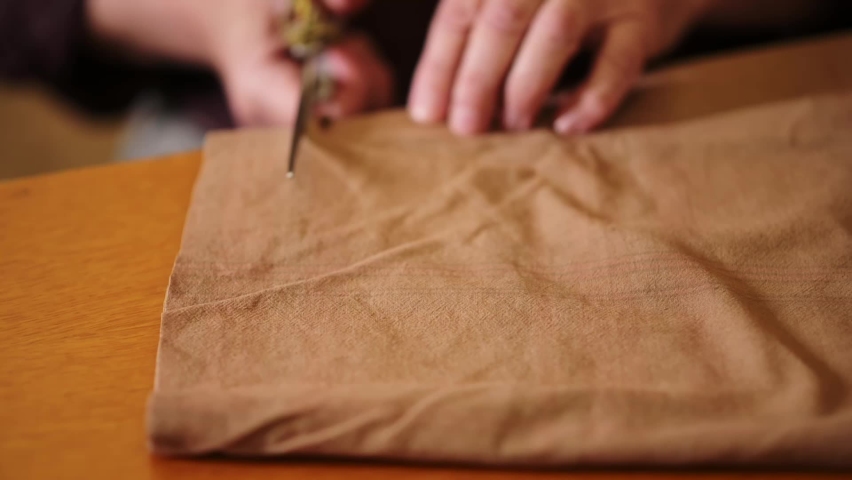 A man cuts fabric with old scissors