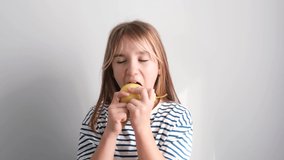 Adorable little school-age girl eating a ripe pear, white background. 4k video