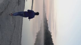 Vertical video. A female photographer came to the shore of Lake Svityaz. Photographs the morning fog and sunrise. Shot on a drone.