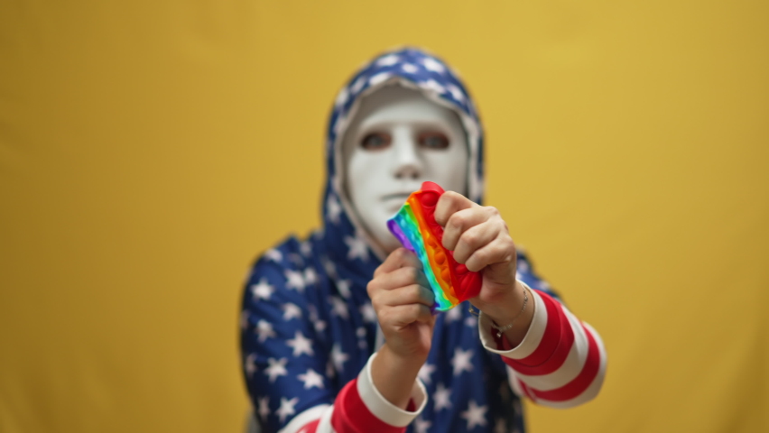 Close-up twisting fidget toy in slow motion with blurred woman in disguise face mask at yellow background. Unrecognizable angry anxious young lady playing anti-stress toy