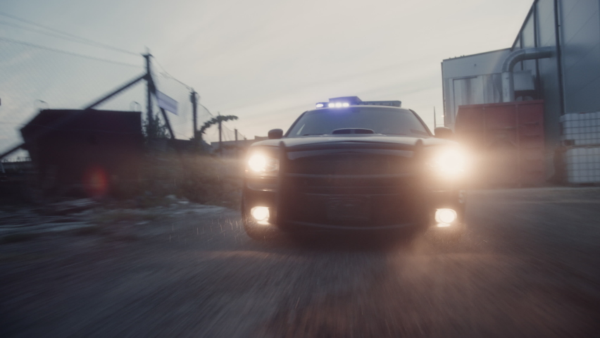 Traffic Patrol Car in Pursuit through Industrial Area. Police Officers Driving Squad Car, Chasing Suspect on Industrial Road, Sirens, High Speed. Cops on Emergency Response Call. Cinematic Action