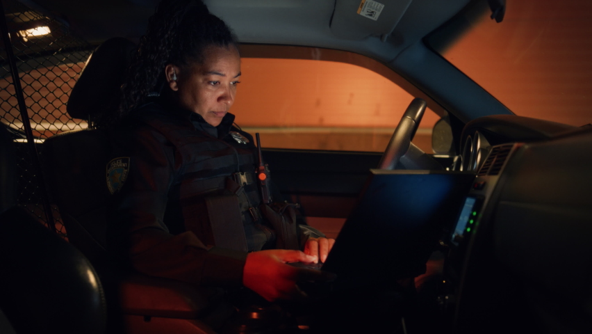 Inside Police Traffic Patrol Squad Car: Black Female Police Officer on Duty Uses Laptop to Check Crime Suspect Background, License Plate, License and Registration. Officer of the Law Fight Crime | Shutterstock HD Video #1095135045