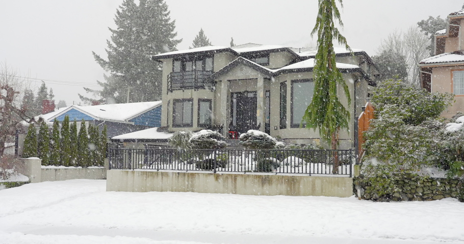 Establishing shot of two story stucco luxury house with big tree and nice landscape at winter snowfall in Vancouver, Canada, North America. Day time on December 2021. ProRes 422 HQ.