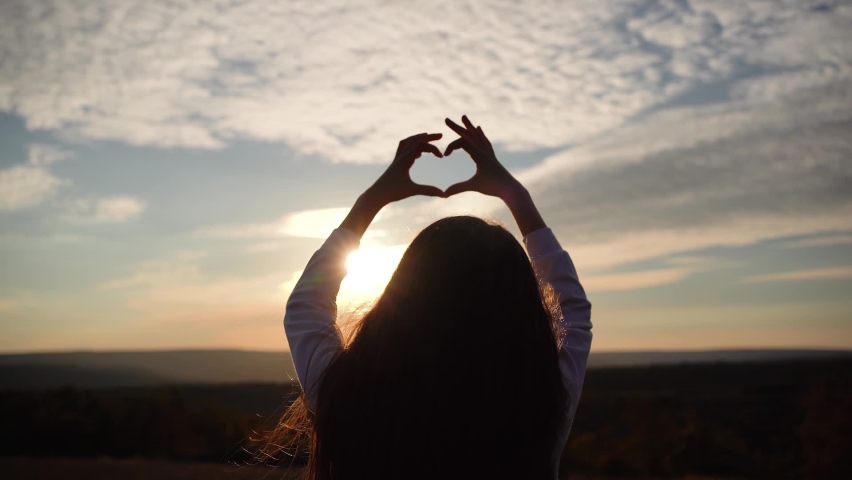 Kid making heart hands against the blue sky, child hands forming a heart shape with sunset silhouette. The magical rays of the sun shine through fingers. Fantastic bright light. Symbol of love. | Shutterstock HD Video #1095147331
