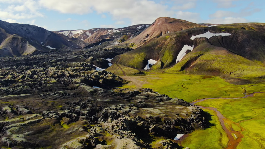 aerial view drone of landmmannalaugar hiking destination sunny day,verdant icelandic landscape and colorful rhyolite mountains,flying over lava field