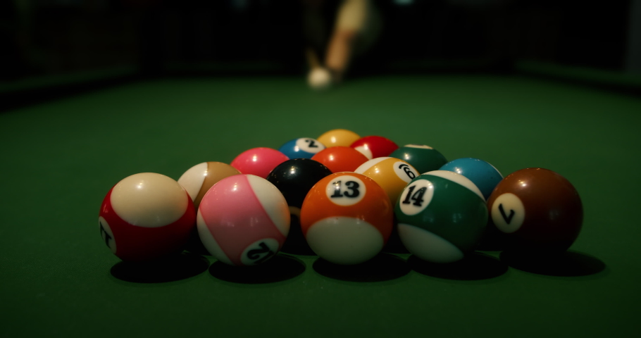 Billiard balls triangle starting position shot. Pool balls with numbers organized in form of pyramid on a green cloth table. white cue ball seen in a distance.Sports game of billiards on green cloth. | Shutterstock HD Video #1095148841