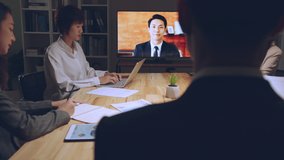 Business people group remote meeting with manager leader via video call conference virtual meeting on tv screen in office at night - Powered by Shutterstock - Get 15% off with code: PIKWIZARD15