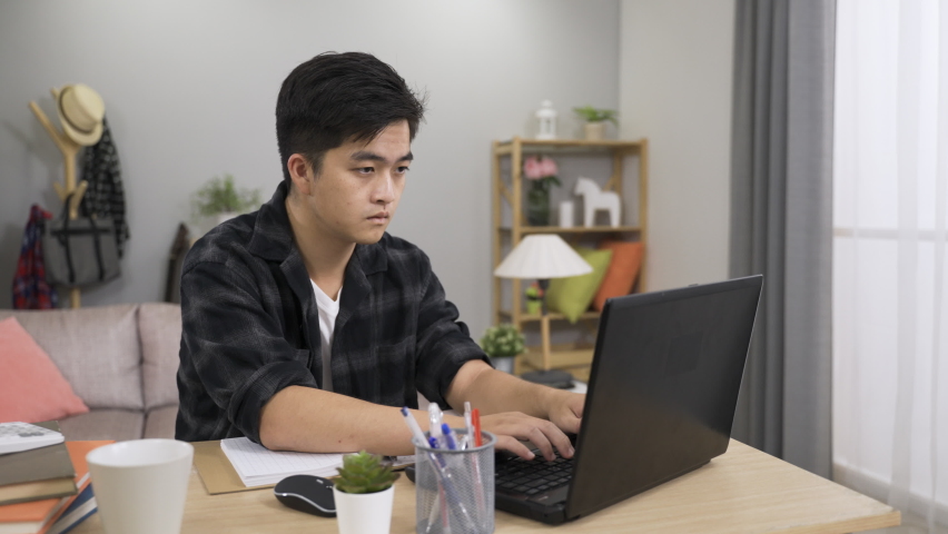 furious asian male is cursing angrily feeling annoyed with an unexpected error on computer device while working from home on a project in the living room Royalty-Free Stock Footage #1095156683