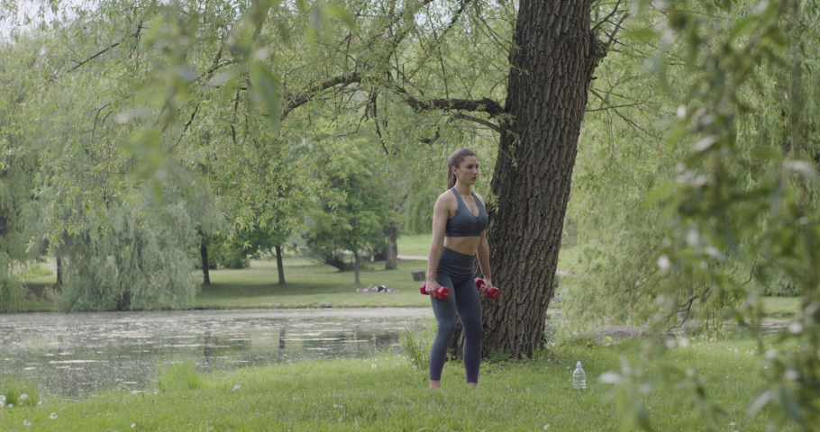 Muscular young bodybuilder exercising Crossfit. Woman in sportswear doing a workout in the park