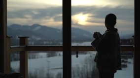 Young woman is drinking tea or coffee while she looking through window at home - Powered by Shutterstock - Get 15% off with code: PIKWIZARD15