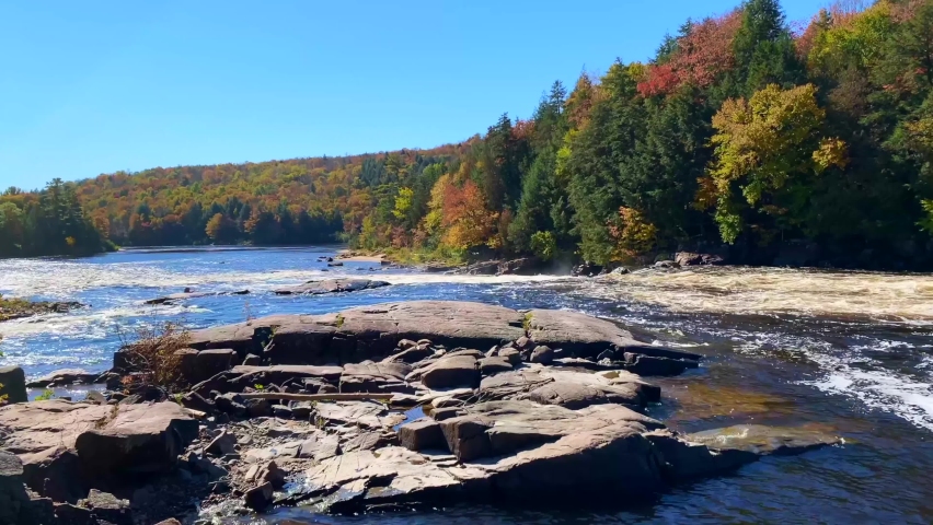 Scenic view on the water falls of Rivière Rouge in Quebec, with the autumn colourful forest in the background