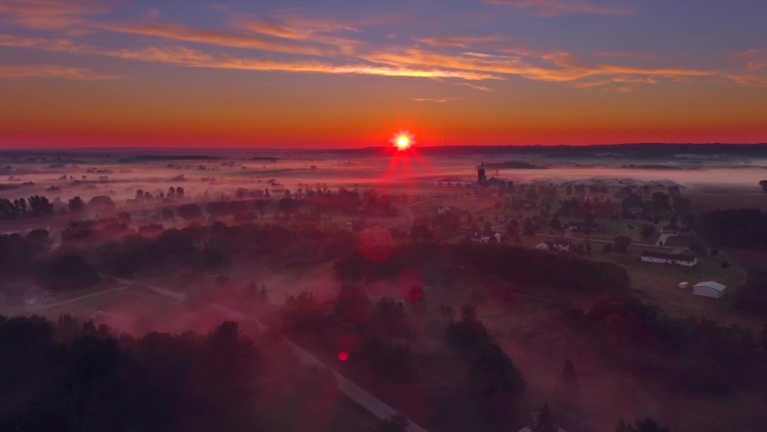 Red sunrise over foggy rural neighborhood at sunrise
