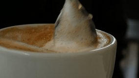 Teaspoon mixes the froth of the Italian cappuccino in the cup