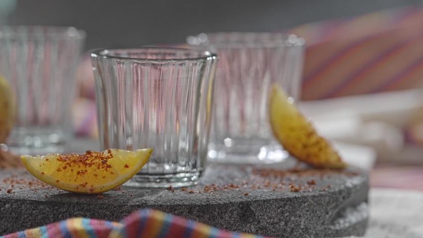 Pouring several glasses of Mexican Mezcal or Tequila shot.
Aged Mexican Mezcal served with orange fruit wedges. | Shutterstock HD Video #1095184175