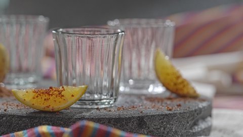 Стоковое видео: Pouring several glasses of Mexican Mezcal or Tequila shot.
Aged Mexican Mezcal served with orange fruit wedges.