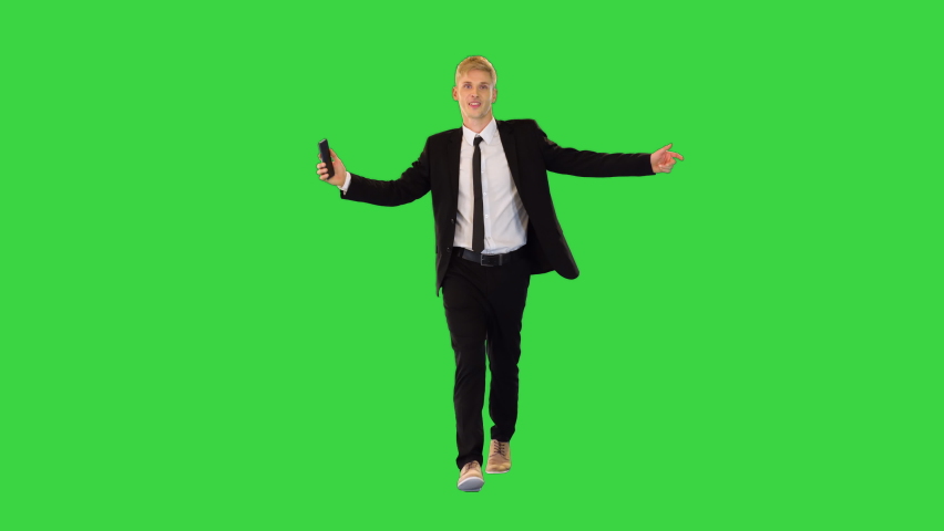 Very pleased young businessman walks talking on phone on a Green Screen, Chroma Key.